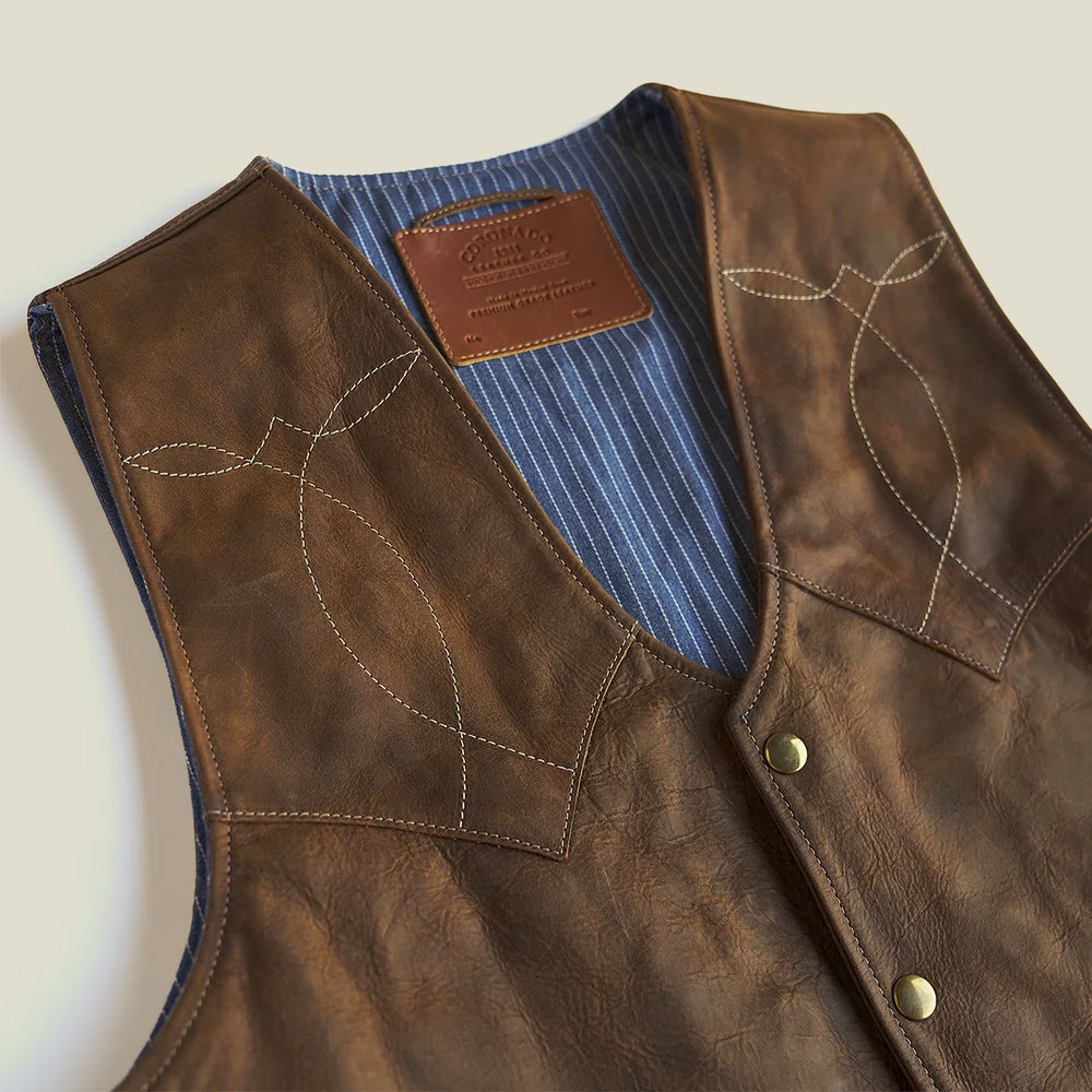 Pointed brown leather front yokes with decorative stitching and blue pinstriped chambray interior