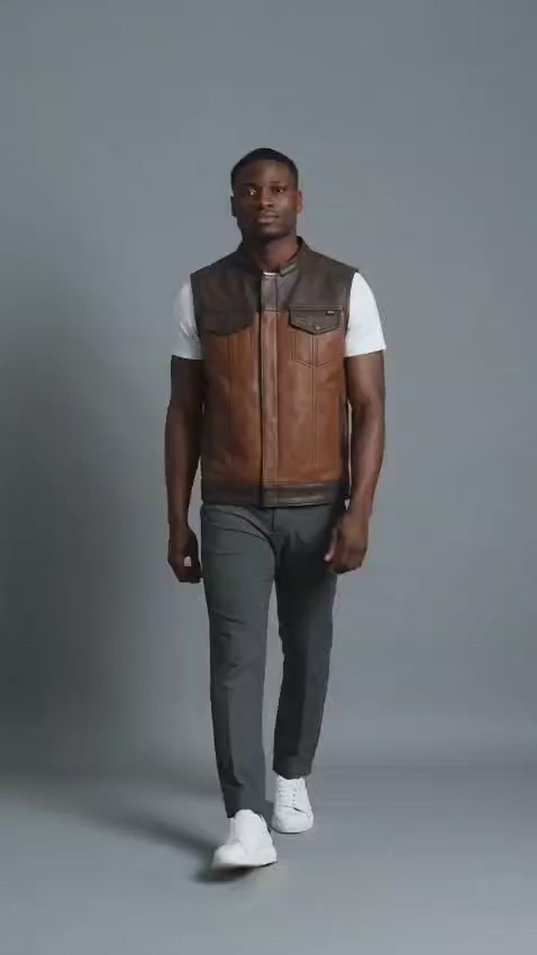 Man modeling a two-tone brown leather biker club vest in a studio