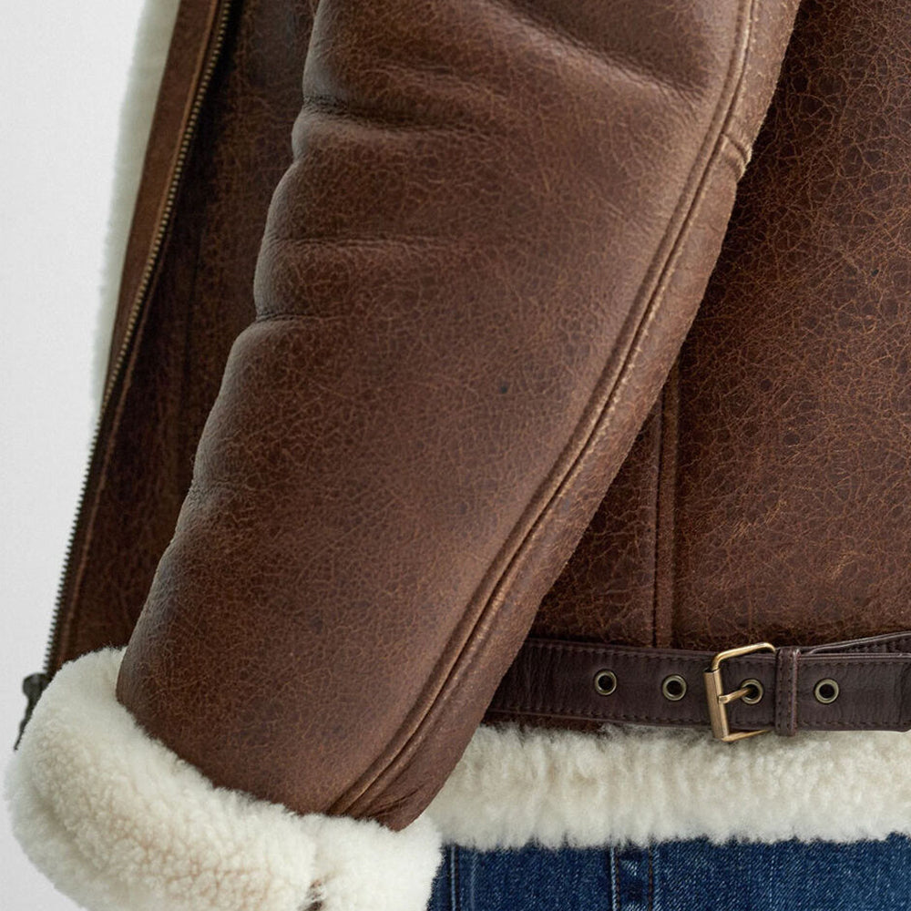 Close up of sleeve detail showing dark brown leather welted piping and side waist buckle strap on RAF aviator jacket