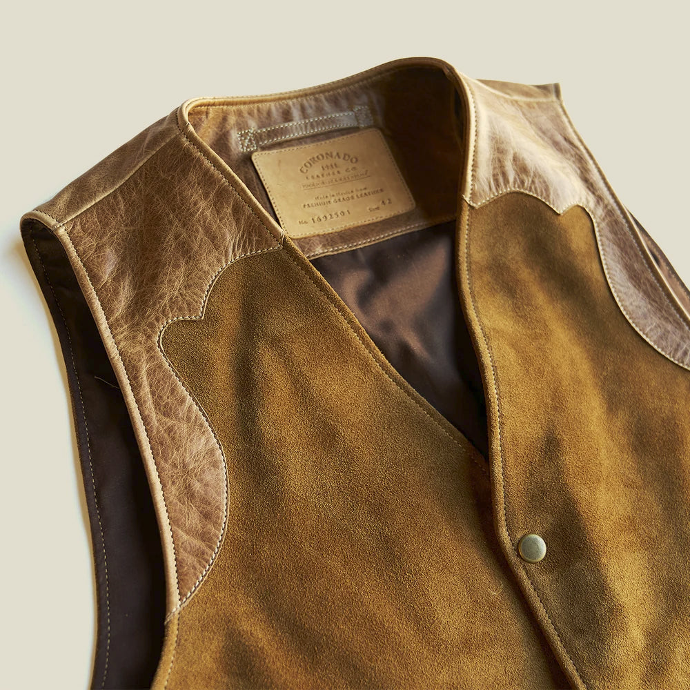 Close-up of the scalloped top-grain leather shoulder yoke, bound V-neck edge and brushed tan suede body