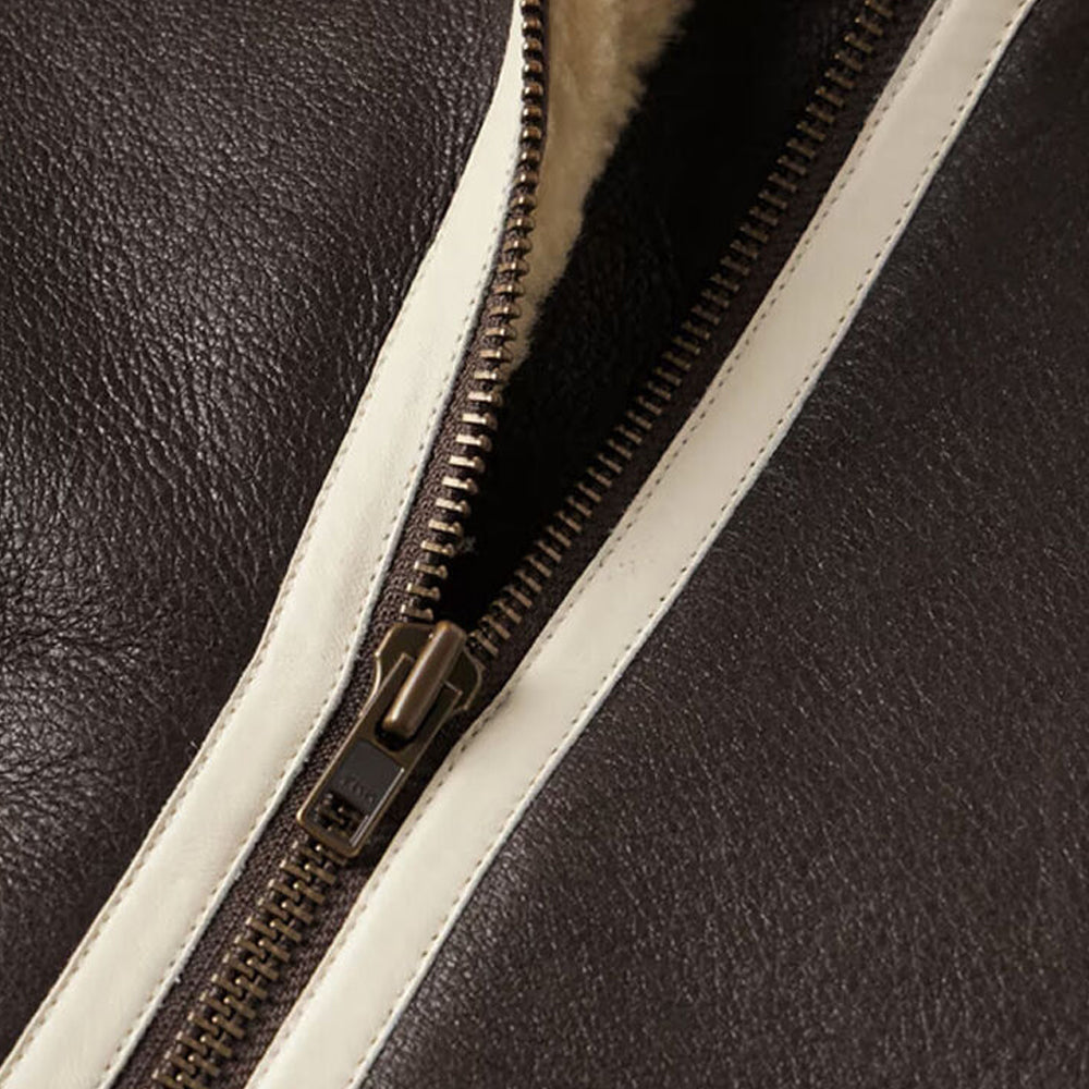Close up detail of antique bronze YKK zipper track bordered by off-white leather seam welting
