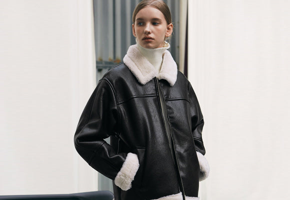 Black leather jacket with oversized white shearling fur collar and cuffs - genuine sheepskin craftsmanship detail