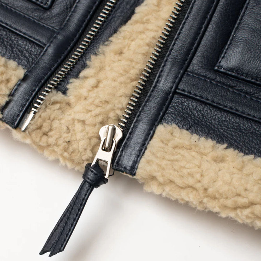 Detail of silver front metal zipper with leather pull-tab and exposed plush beige shearling bottom hem