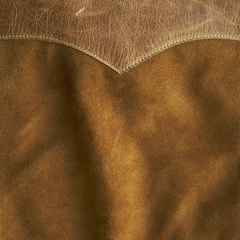 Macro detail of warm tan steerhide suede nap beneath the lighter top-grain Western yoke edge