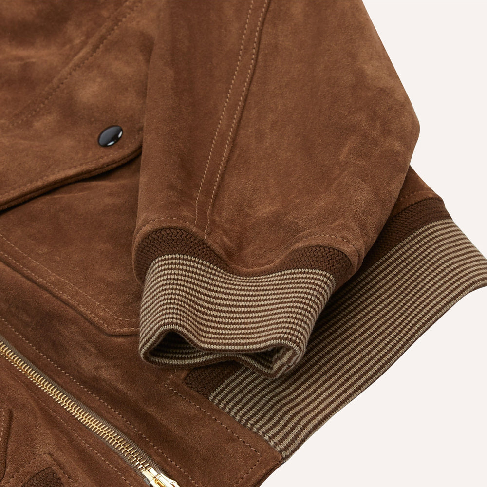 Close-up of brown and cream striped rib-knit cuff and waistband on a tobacco suede bomber jacket.