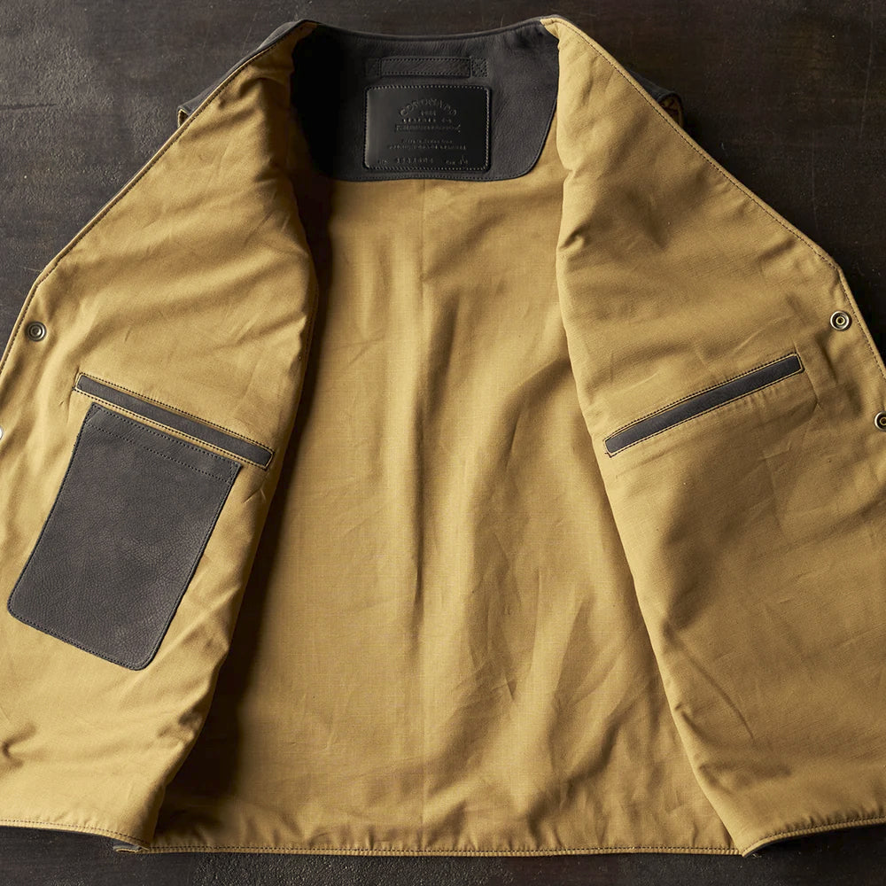 Open interior of the cowboy vest showing tan cotton ripstop lining, a leather patch pocket and a narrow welt pocket