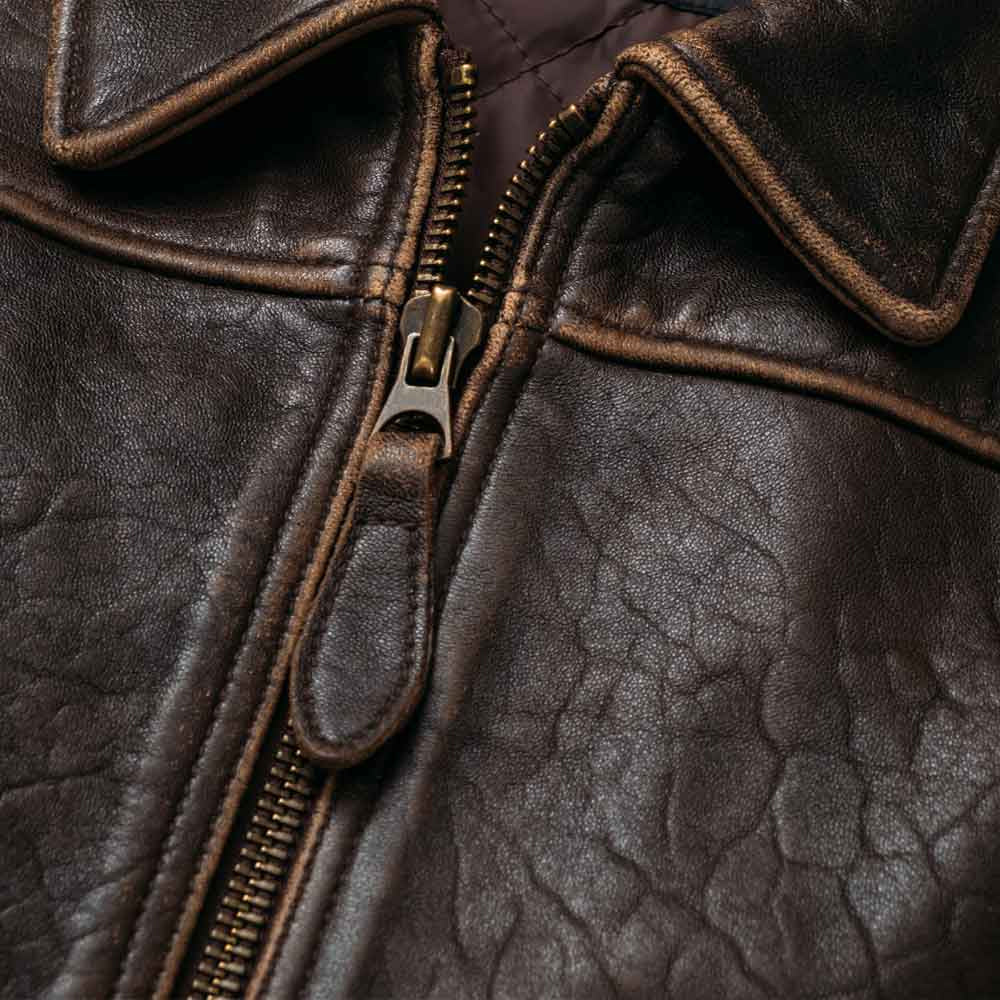 Detailed point collar and antique-tone front zipper with leather pull on distressed sheepskin bomber jacket
