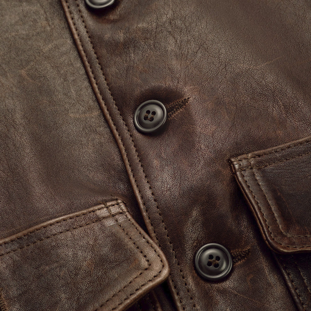 Close detail of dark tonal buttons, stitched buttonholes and natural grain on hand-waxed brown lambskin