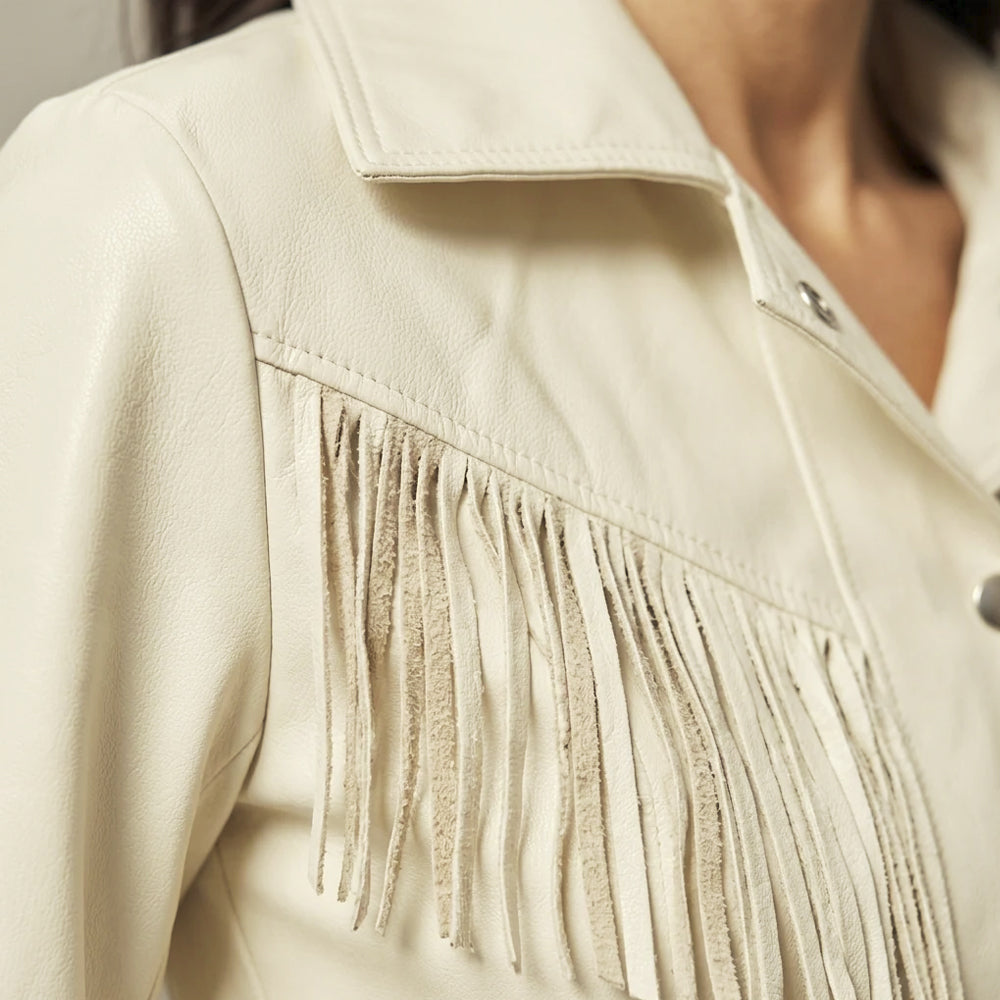 Close-up of a white leather jumpsuit’s pointed collar, stitched chest yoke and individually cut fringe.