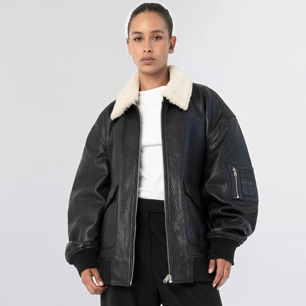 Woman wearing black cow leather bomber jacket open with a cream shearling collar