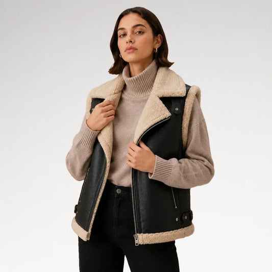 Woman wearing a black leather biker vest with cream faux-shearling lapels over a beige turtleneck