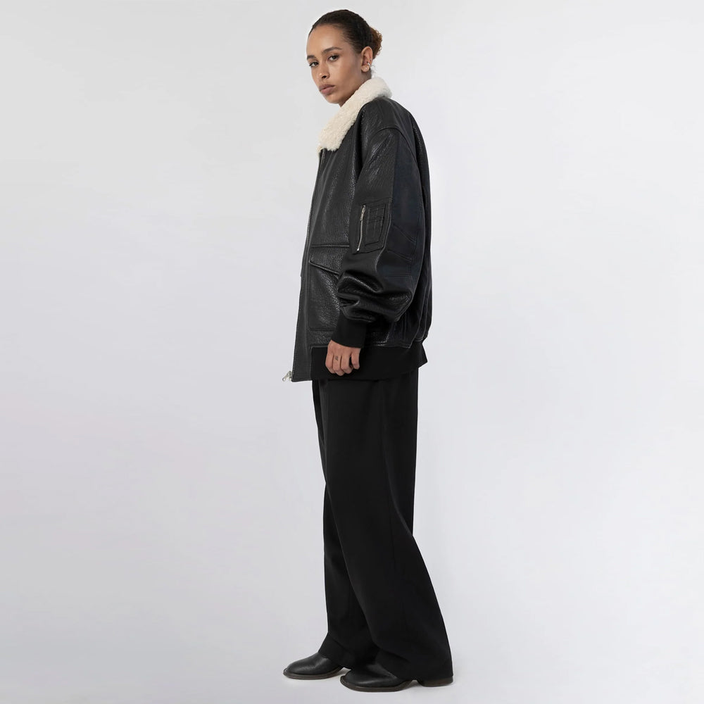 Side view of women’s black leather bomber jacket showing its oversized silhouette