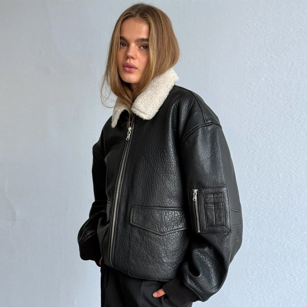 Three-quarter view of women’s black leather bomber jacket with cream collar and sleeve pocket