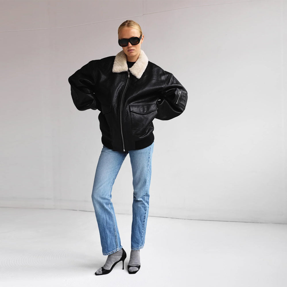 Women’s oversized black leather bomber jacket styled with blue jeans