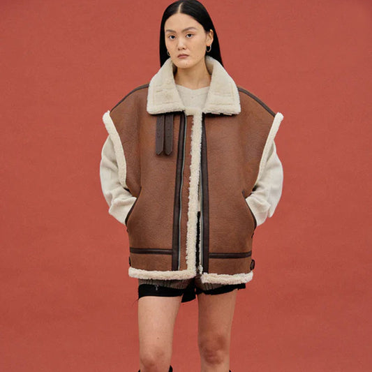 Woman wearing an oversized brown aviator shearling vest with cream wool trim, front view