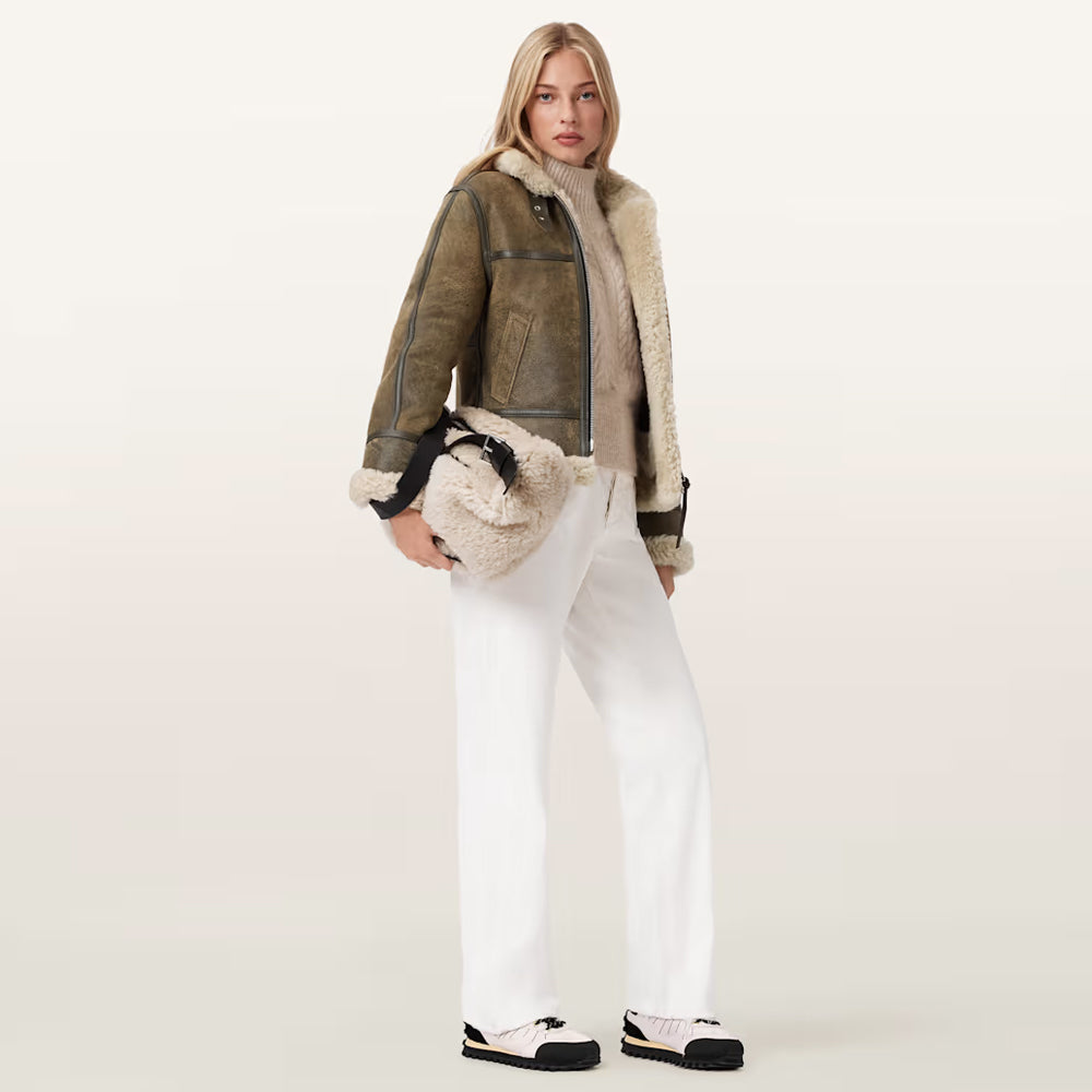 Full-length shot of model in olive cropped shearling aviator jacket over beige sweater.