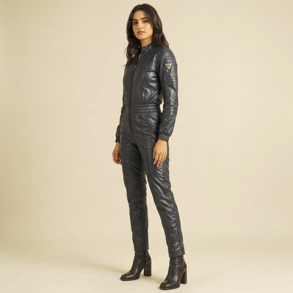 Three-quarter view of a women's leather moto jumpsuit with channel-stitched sleeves and a triangular upper-arm badge.