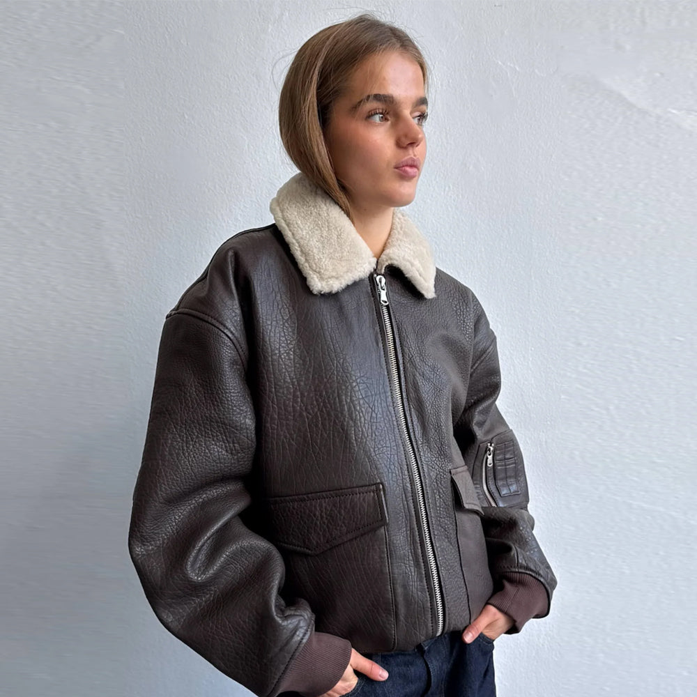 Woman wearing an oversized brown cow leather bomber jacket with cream shearling collar