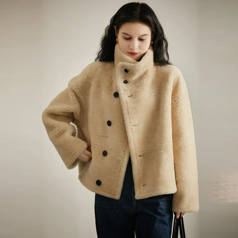 A woman demonstrates the reversible feature of the brown sheepskin jacket, showcasing the plush interior fur lining.