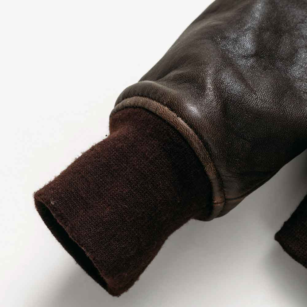 Close-up of wool-blend rib-knit cuff attached to the weathered sheepskin sleeve with leather-bound seam
