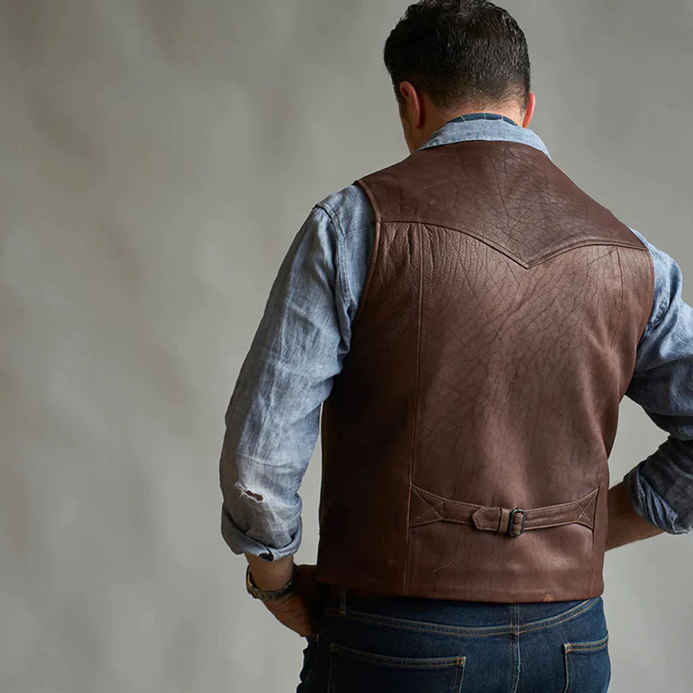 Rear view of a man showcasing the pointed back yoke and adjustable buckle strap of the brown western vest.