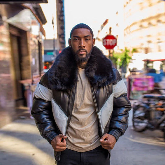A model standing in the street wearing the men's black and white lambskin leather V-bomber jacket in a full front view pose.