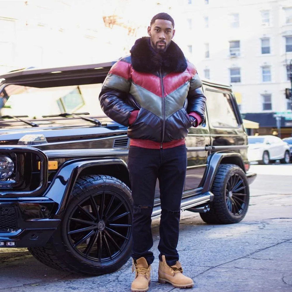 Front view of a model in the street wearing the men's red green and black lambskin leather V-bomber jacket with hands in pockets.