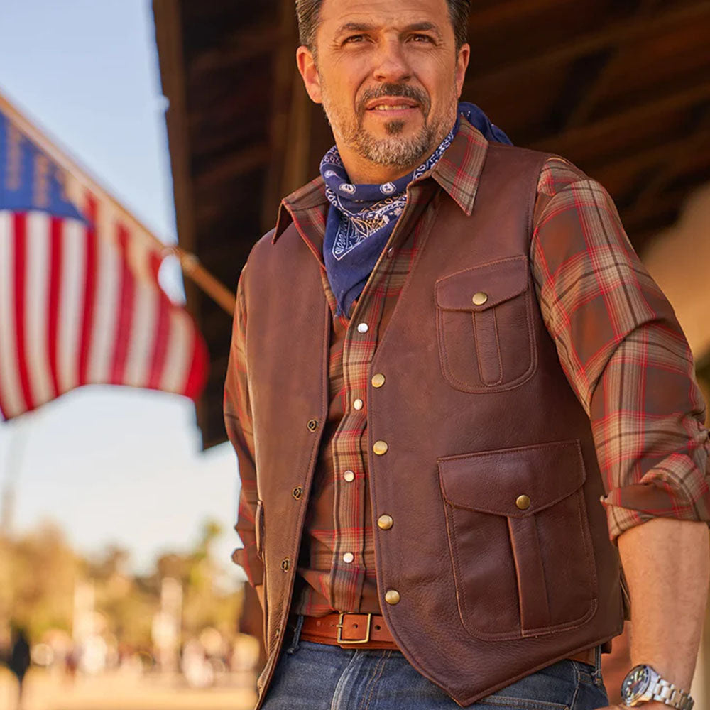 Outdoor lifestyle display of a man styling the brown multi-pocket buckskin vest over a red plaid flannel shirt and blue jeans.