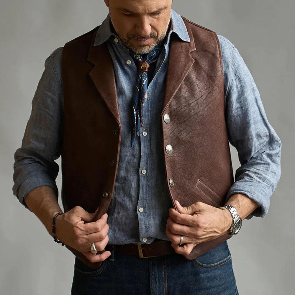 Close-up of a man adjusting the brown western leather vest styled over a blue denim shirt and bandana.